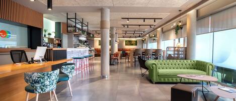Un interior moderno con una mesa de recepción, zona de estar y ventanas amplias.