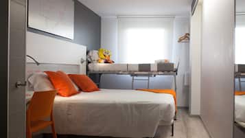 Habitación de hotel compacta con literas, una cama individual, un escritorio y una silla.