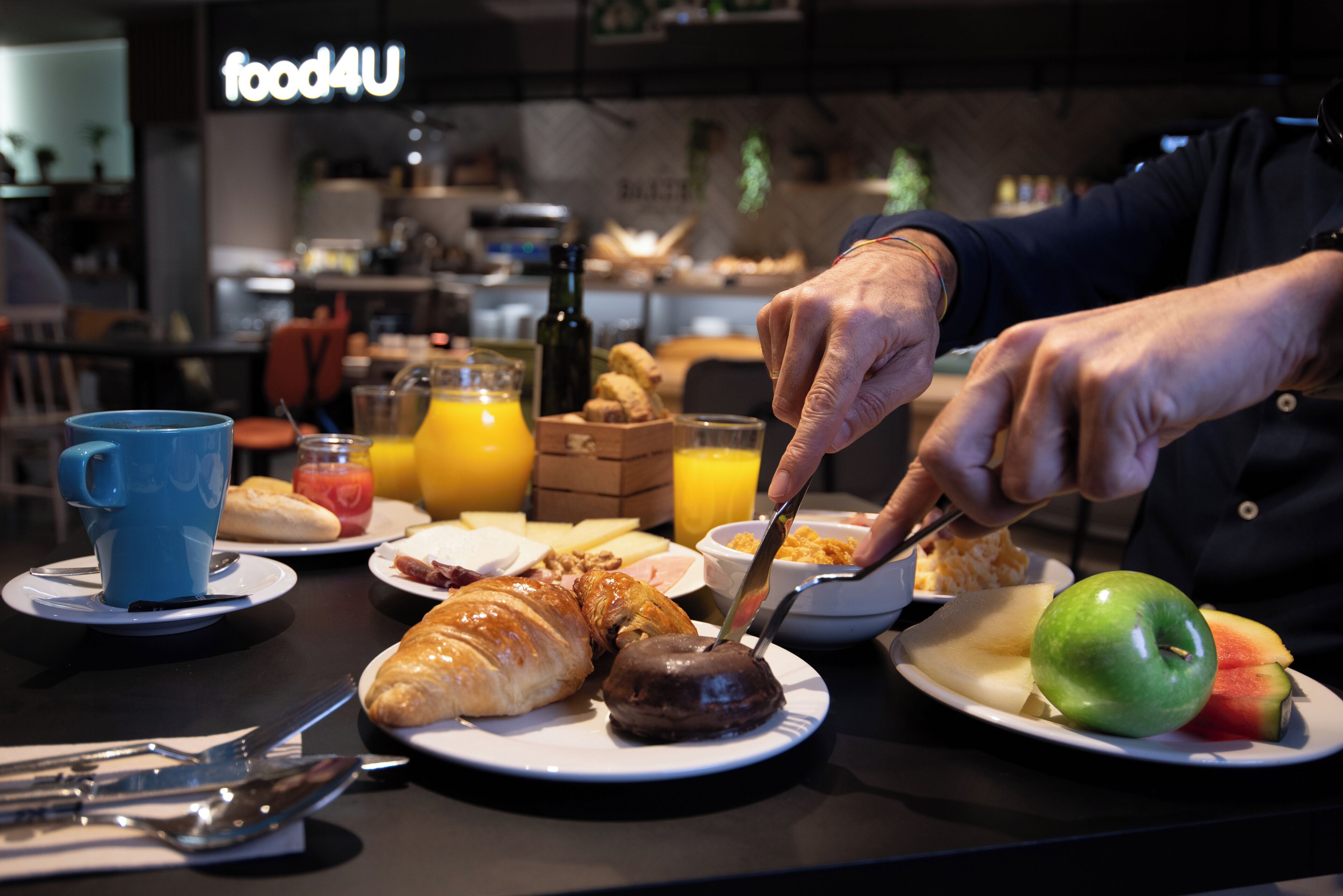 A breakfast setting with croissants, a green apple, and orange juice on plates.