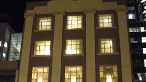 Un immeuble à plusieurs étages, avec des fenêtres illuminées et une enseigne indiquant : « KINGSTON FINE ARTS ».