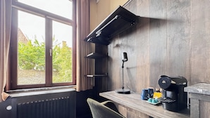 A room with a desk, chair, radiator, window, curtains, and a coffee maker. - Botaniek (Bruges)