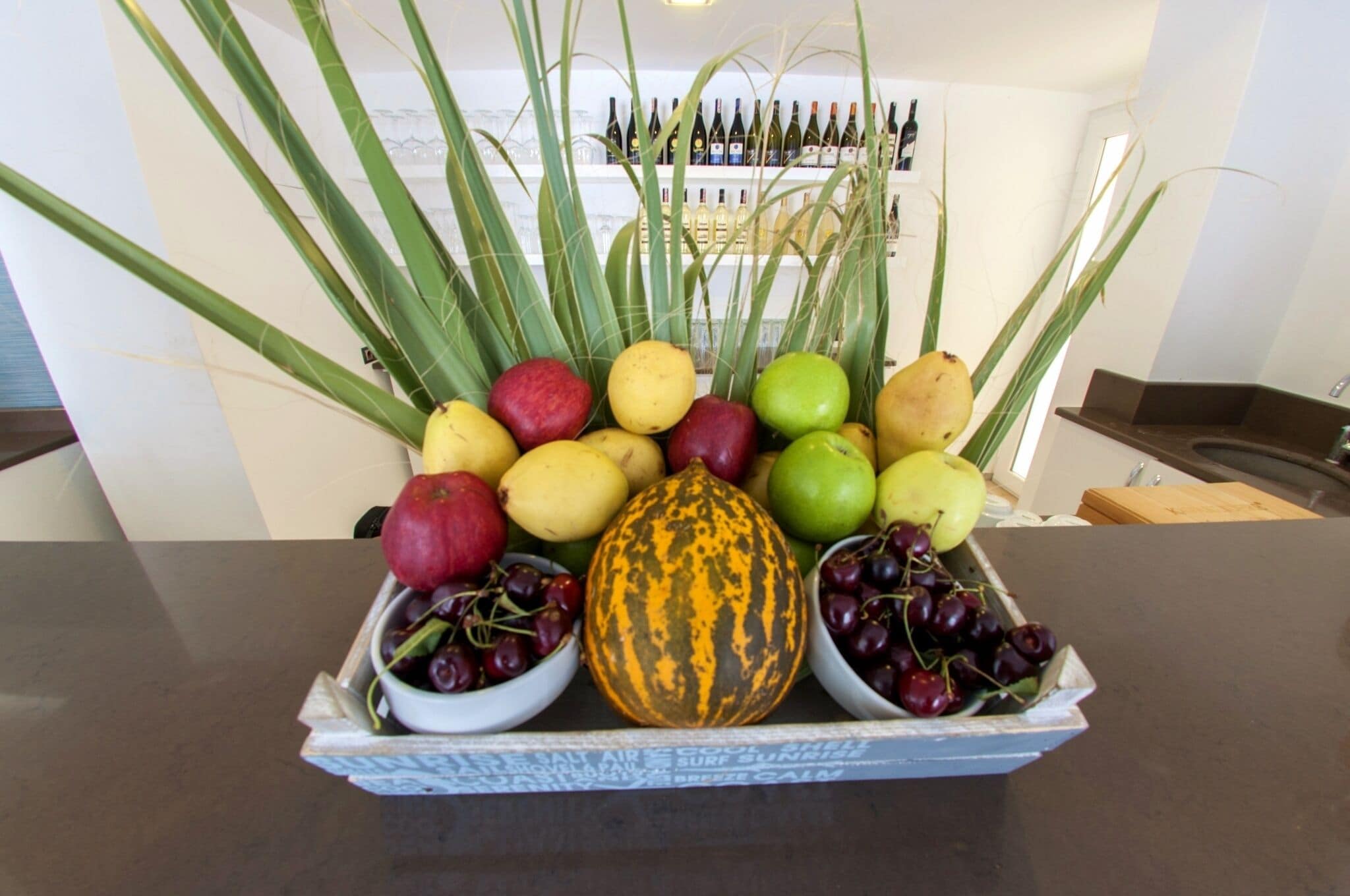 Una exhibición de frutas y verduras con una gran variedad de productos, incluyendo manzanas, uvas y una calabaza.