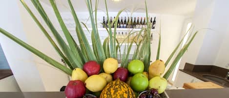 Una exhibición de frutas y verduras con una gran variedad de productos, incluyendo manzanas, uvas y una calabaza.