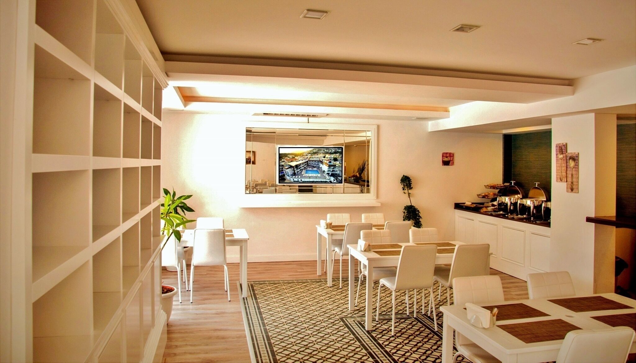 Una habitación de hotel moderna con zona de comedor, televisor en la pared y una barra.