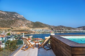 A wooden deck with two chairs and a table overlooking a coastal town and a swimming pool. - Rhapsody Hotel & Spa Kalkan (+12 Adults only) (Kas)