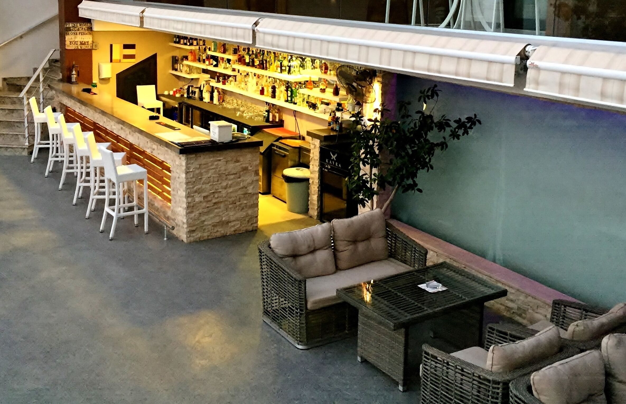 A bar area with a counter, stools, and a seating area with a sofa and a table.