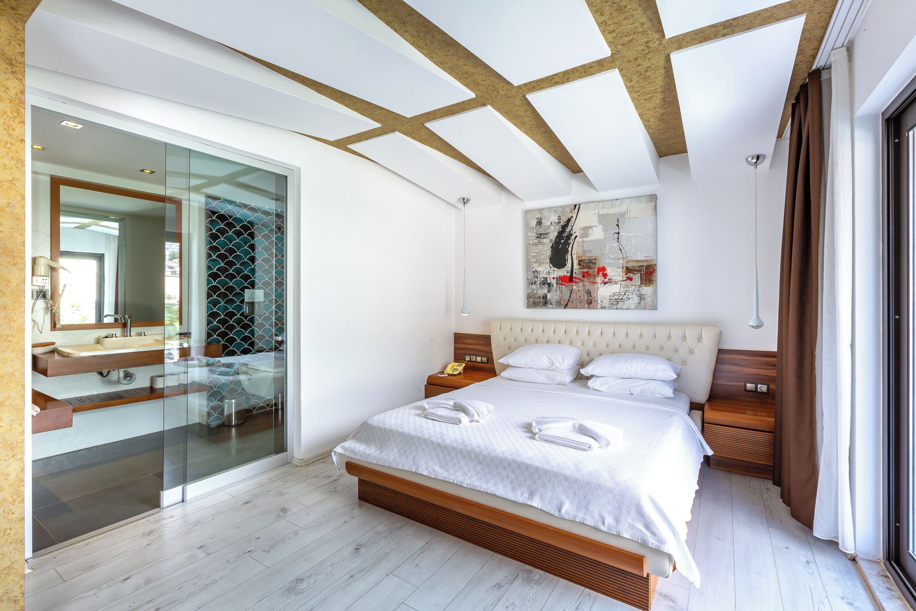 Un dormitorio moderno con una cama grande, cabina de ducha con mamparas de vidrio y una obra de arte urbana en la pared.