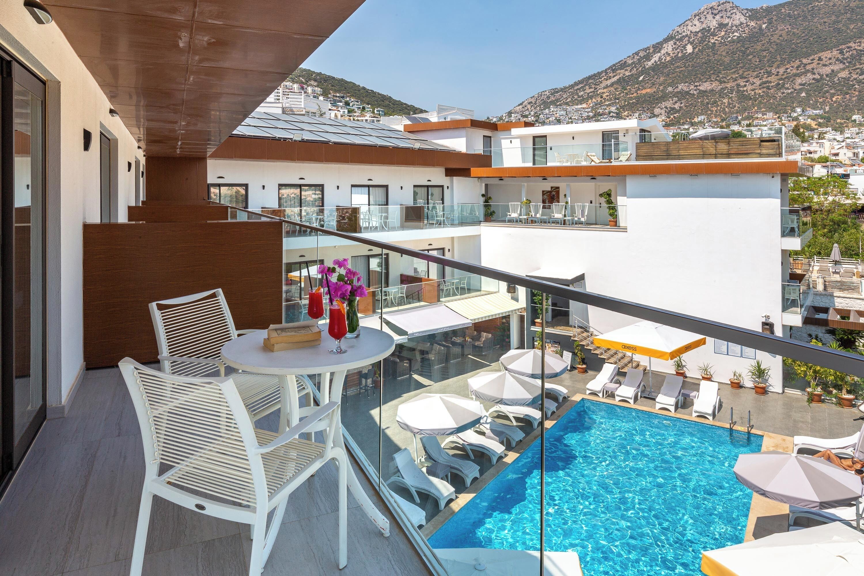 A rooftop pool area with white lounge chairs, a table, and umbrellas.