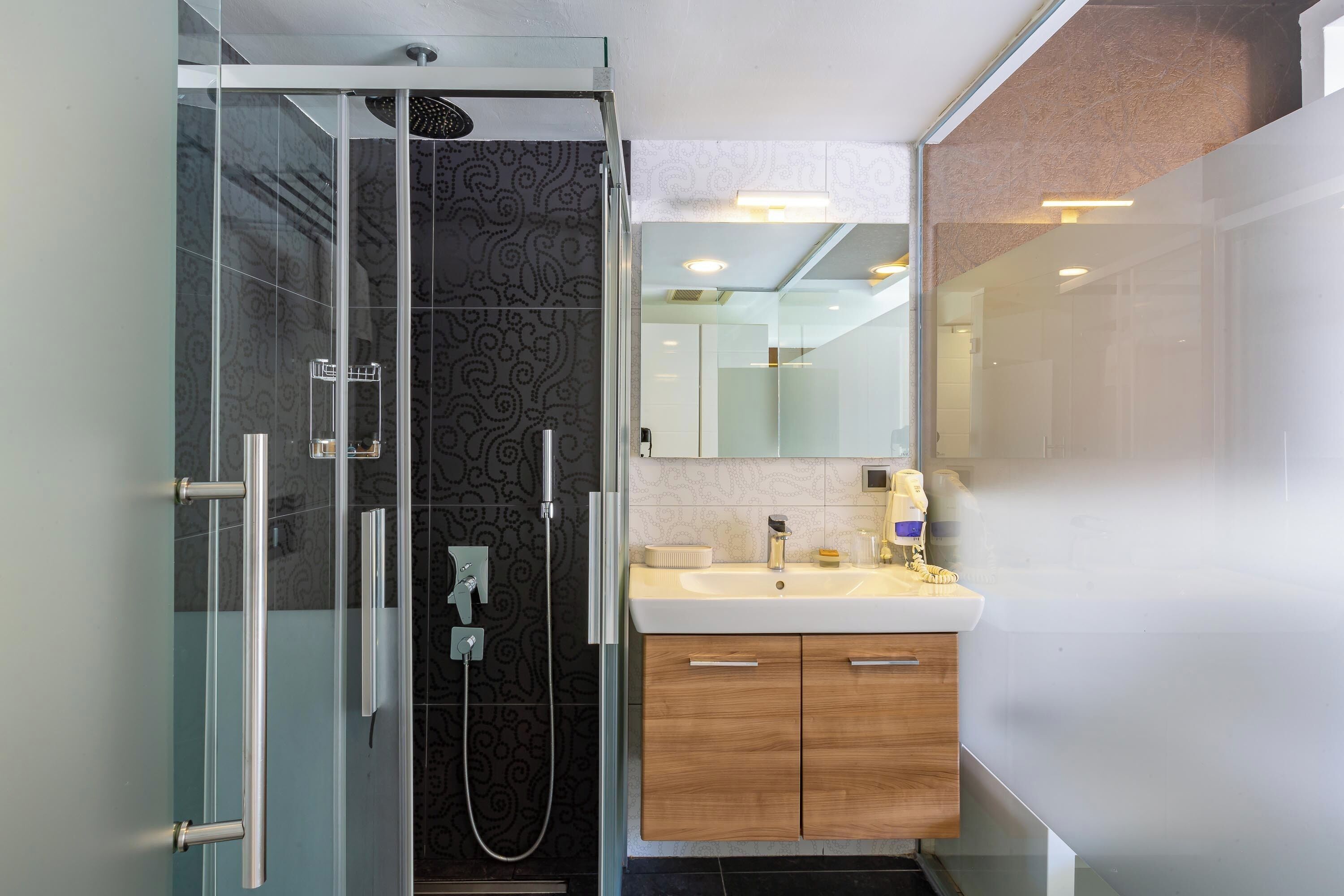A modern bathroom with a glass-enclosed shower, a vanity with a mirror, and a sink.