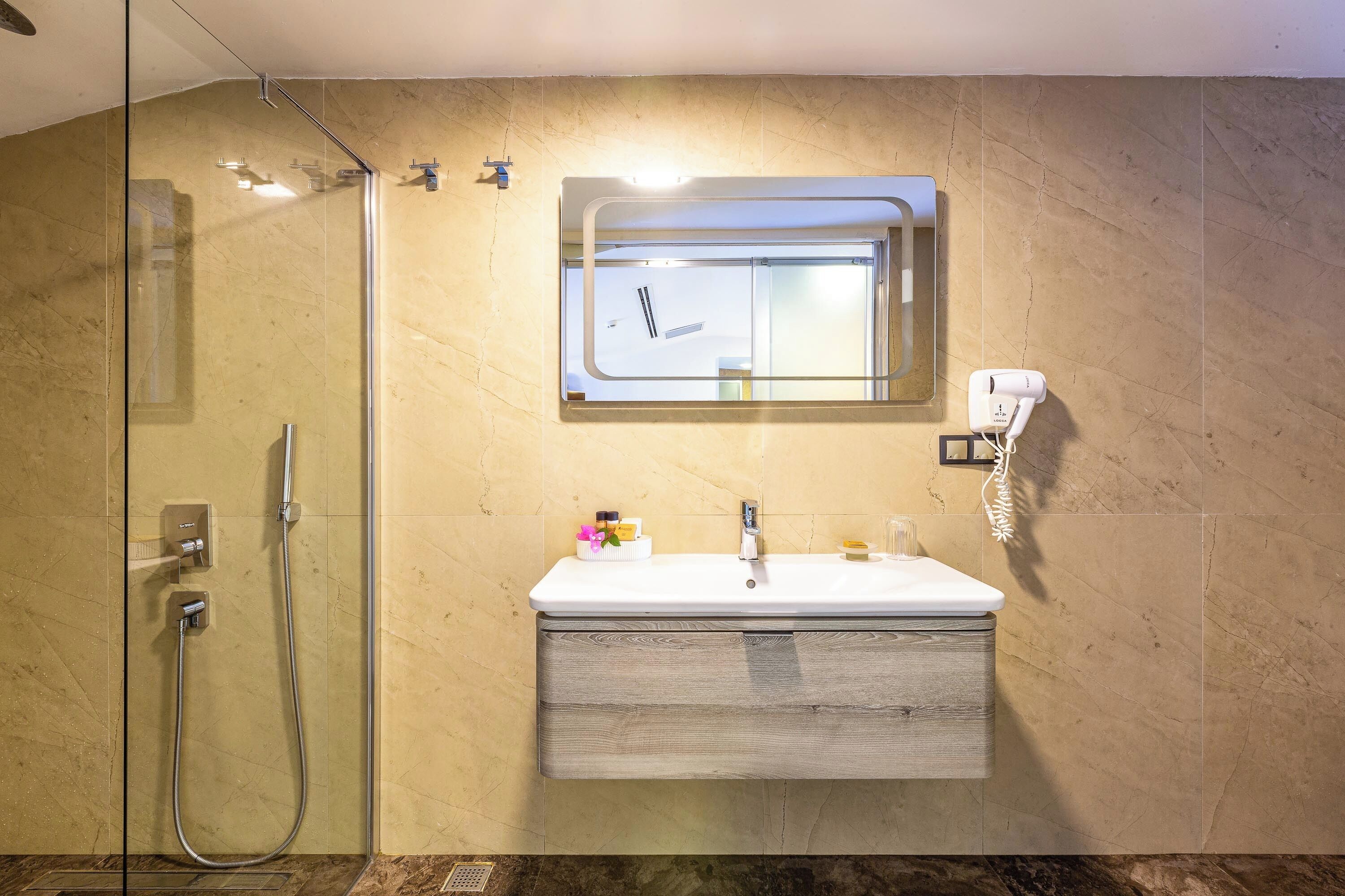 A modern bathroom with a glass-enclosed shower, a vanity with a mirror, and a built-in phone.