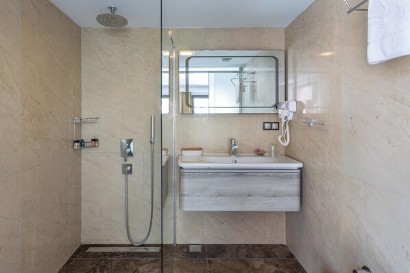 Un baño moderno con ducha de vidrio, tocador con espejo y perchero.
