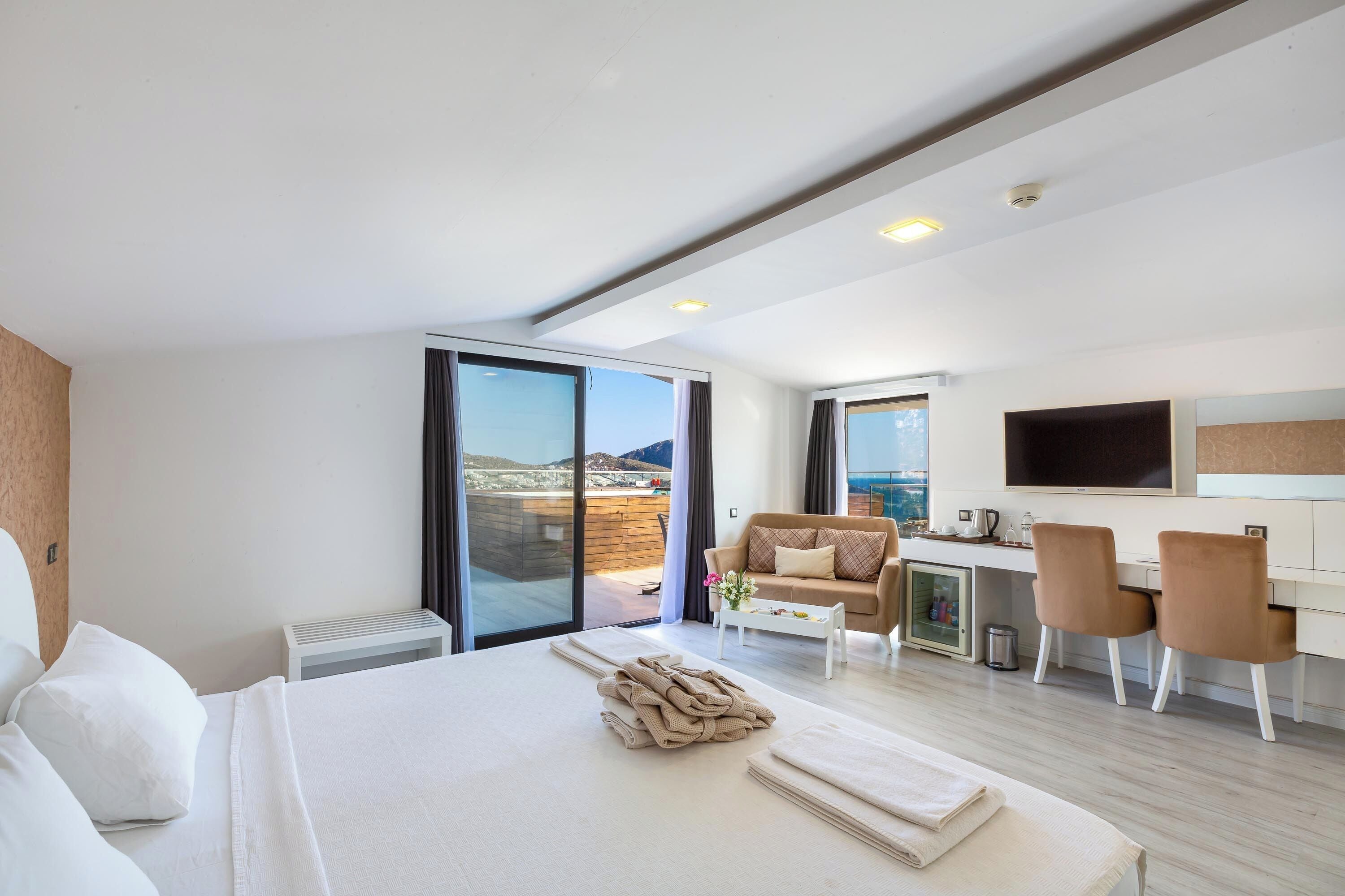 A modern hotel room with a large bed, a desk, and a sofa.