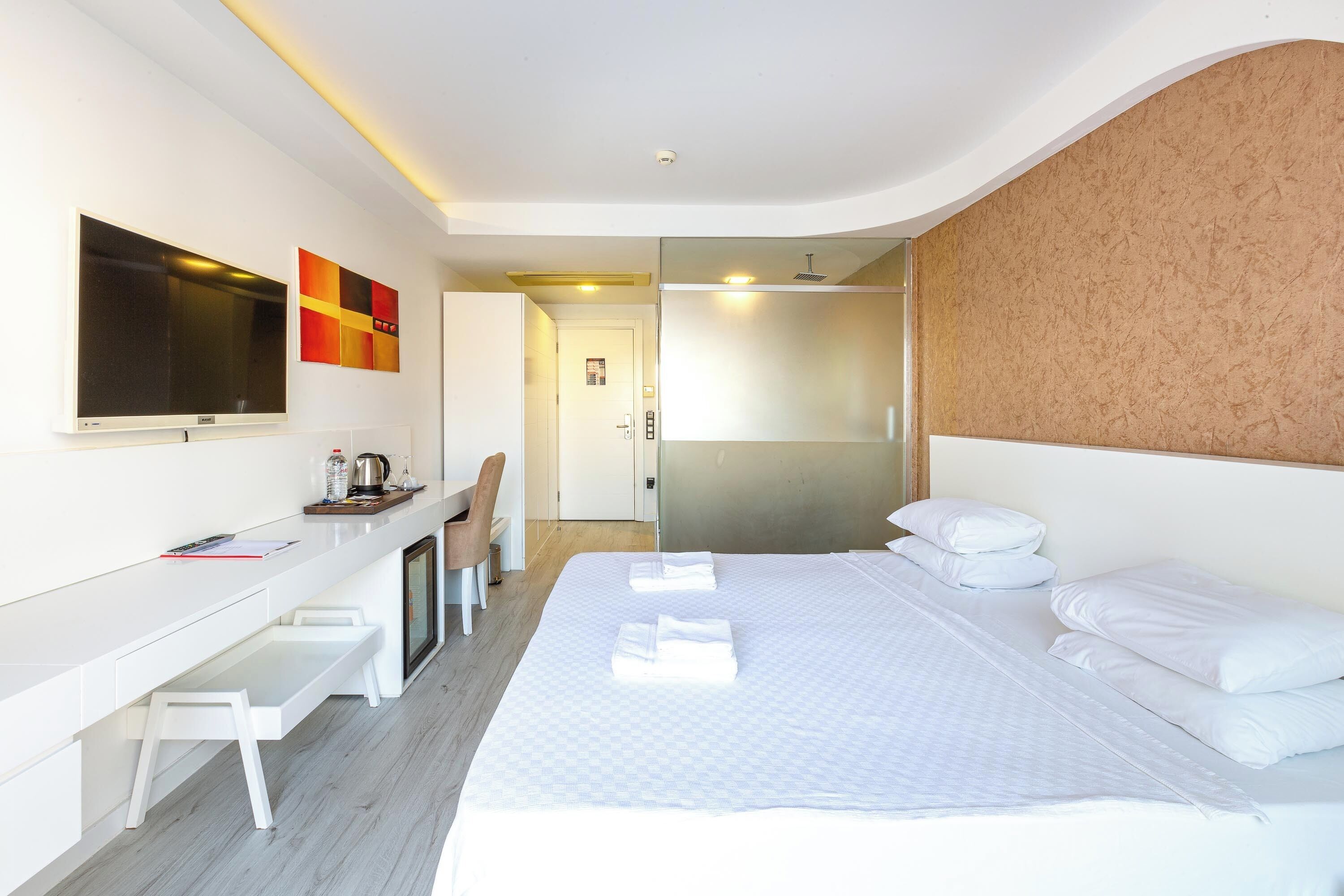 Une chambre d’hôtel moderne équipée d’un grand lit, d’un bureau avec une chaise, d’une télévision et d’un espace douche.