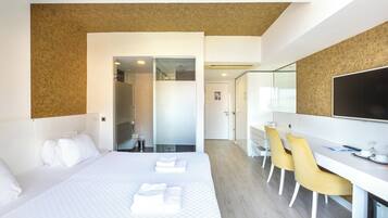 Une chambre d’hôtel moderne avec un grand lit, un bureau avec des chaises et un téléviseur.