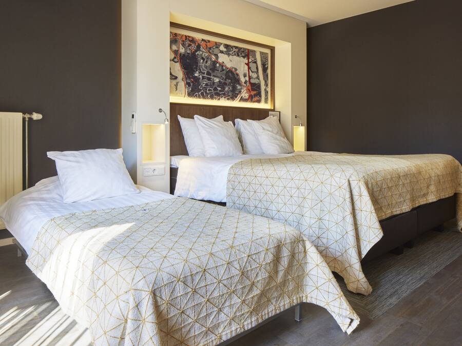 A hotel room with two beds, a large abstract painting on the wall, and a radiator.