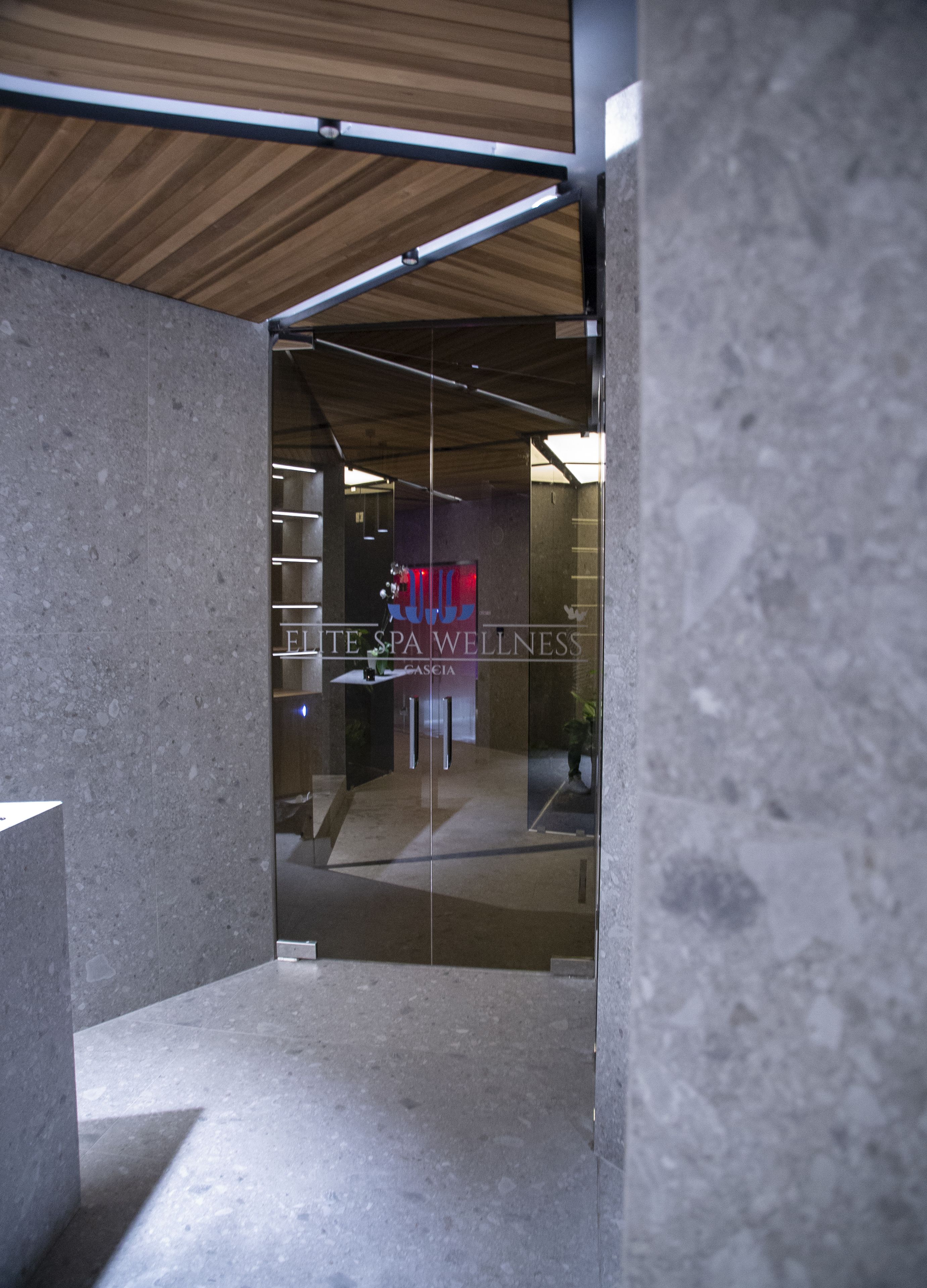 Un interior de spa moderno con una recepción, techo de madera y pared de vidrio.