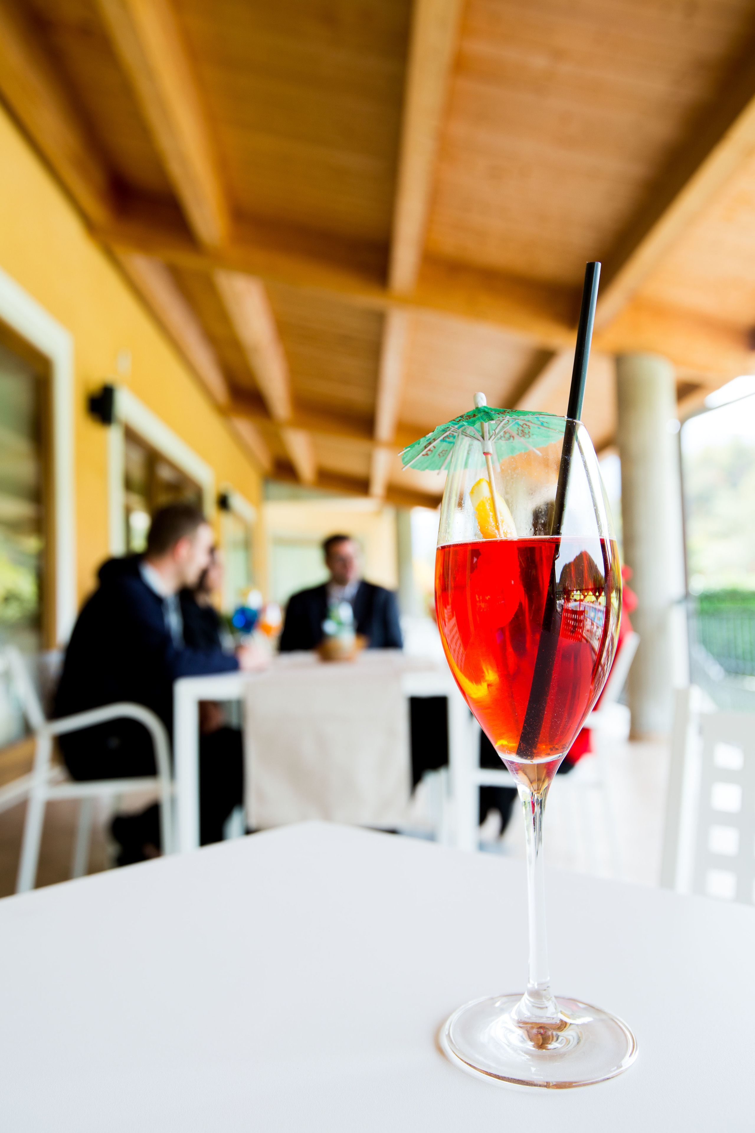 Un vaso de bebida roja con pajita y paraguas sobre una mesa en un restaurante.