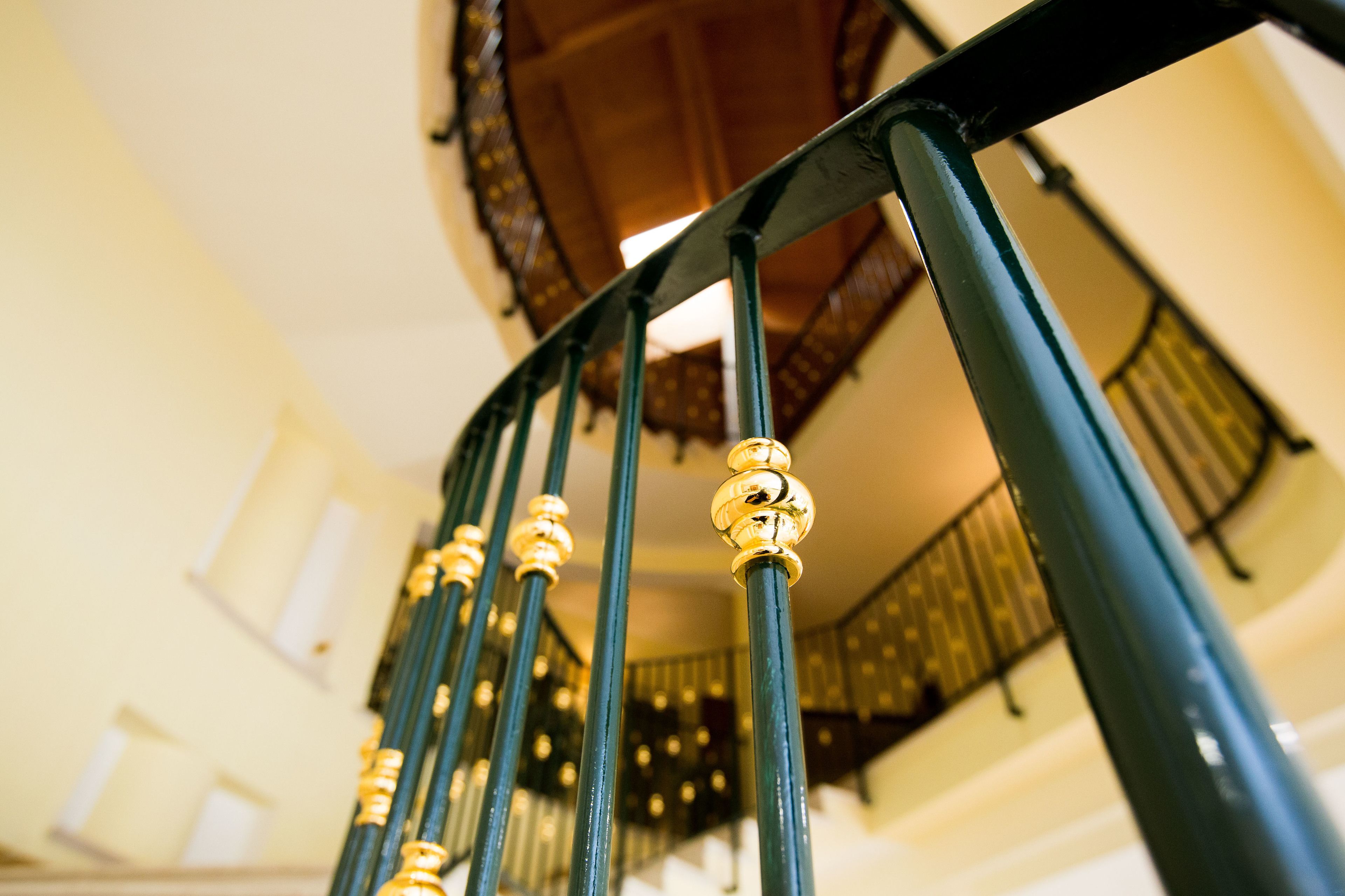 Una escalera con barandillas negras ornamentadas y balaustres dorados.