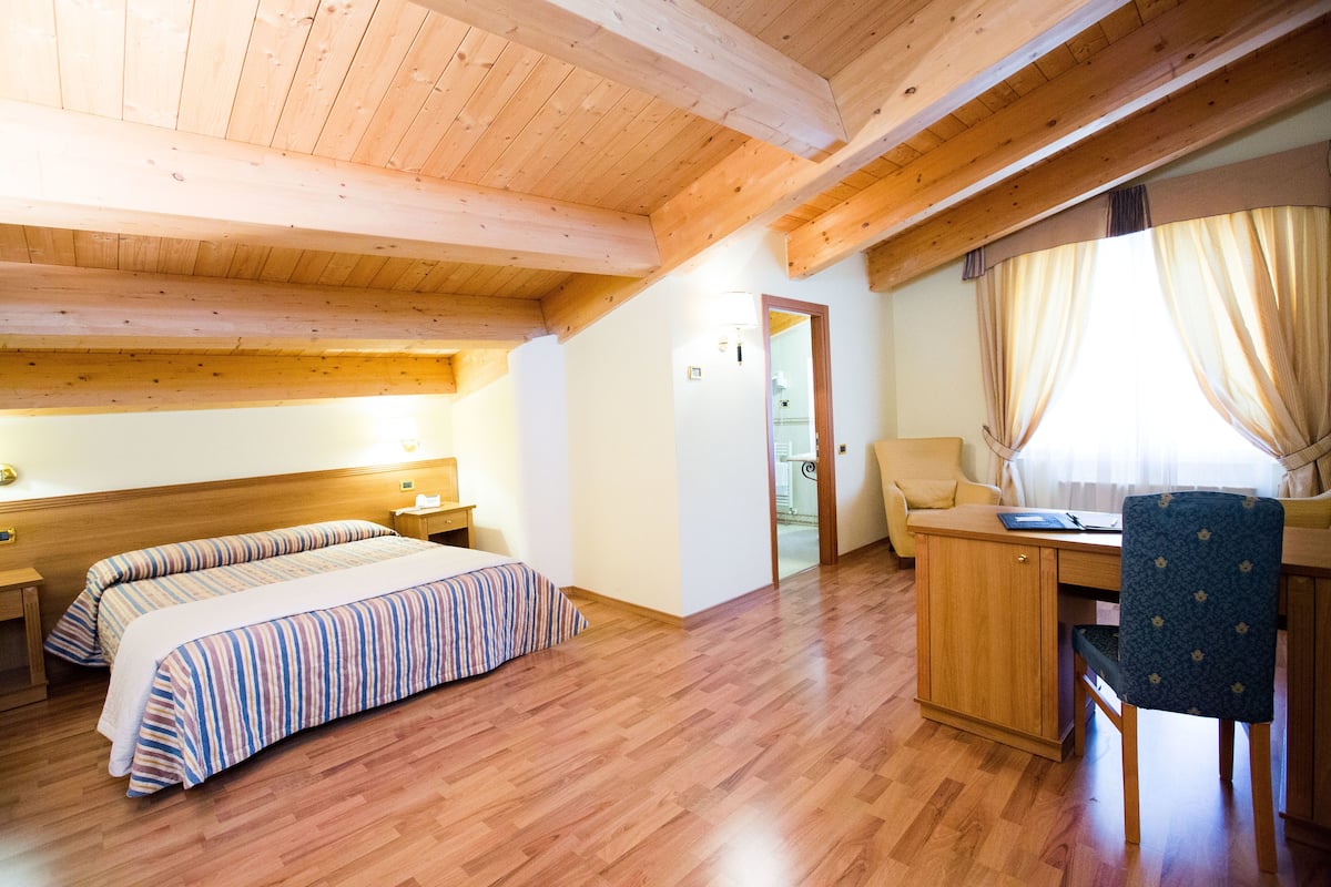 A bedroom with two beds, a desk, a chair, and a wardrobe.