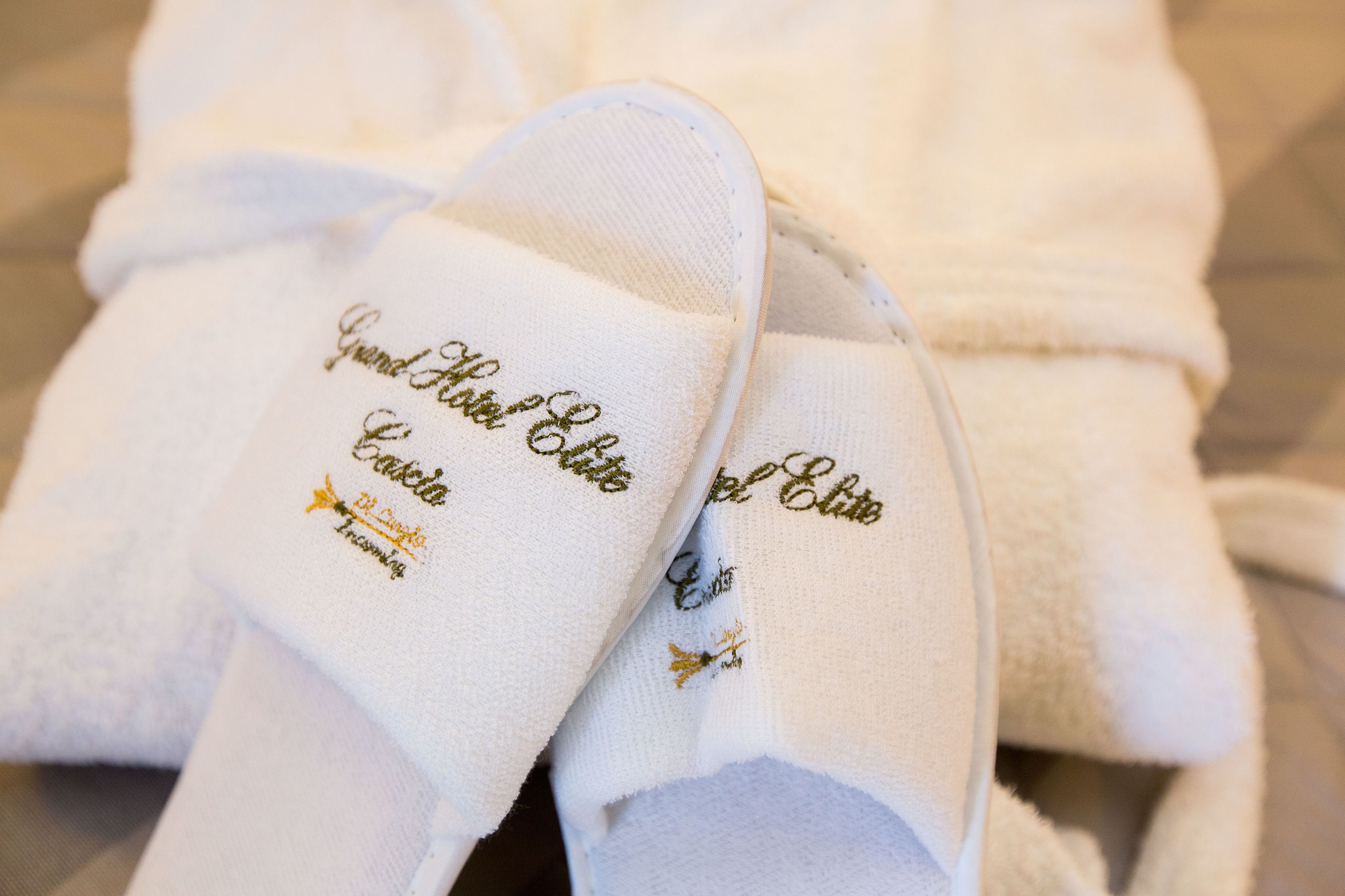 A pair of white bathrobes with embroidered text.