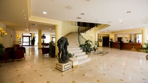 Un hall amplio con una escalera central, zonas de estar y un mostrador de recepción.