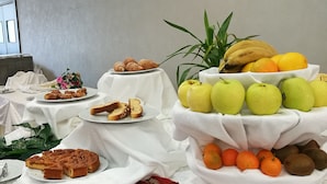 A buffet table with various food items including fruits, pastries, and a decorative plant. - Hotel Village Club Santa Caterina (Scalea)