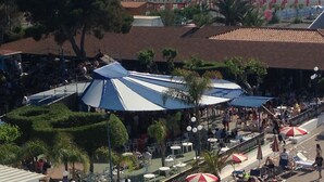 An outdoor seating area with umbrellas, tables, and chairs, overlooking a beach and a coastal promenade. - Hotel Village Club Santa Caterina (Scalea)