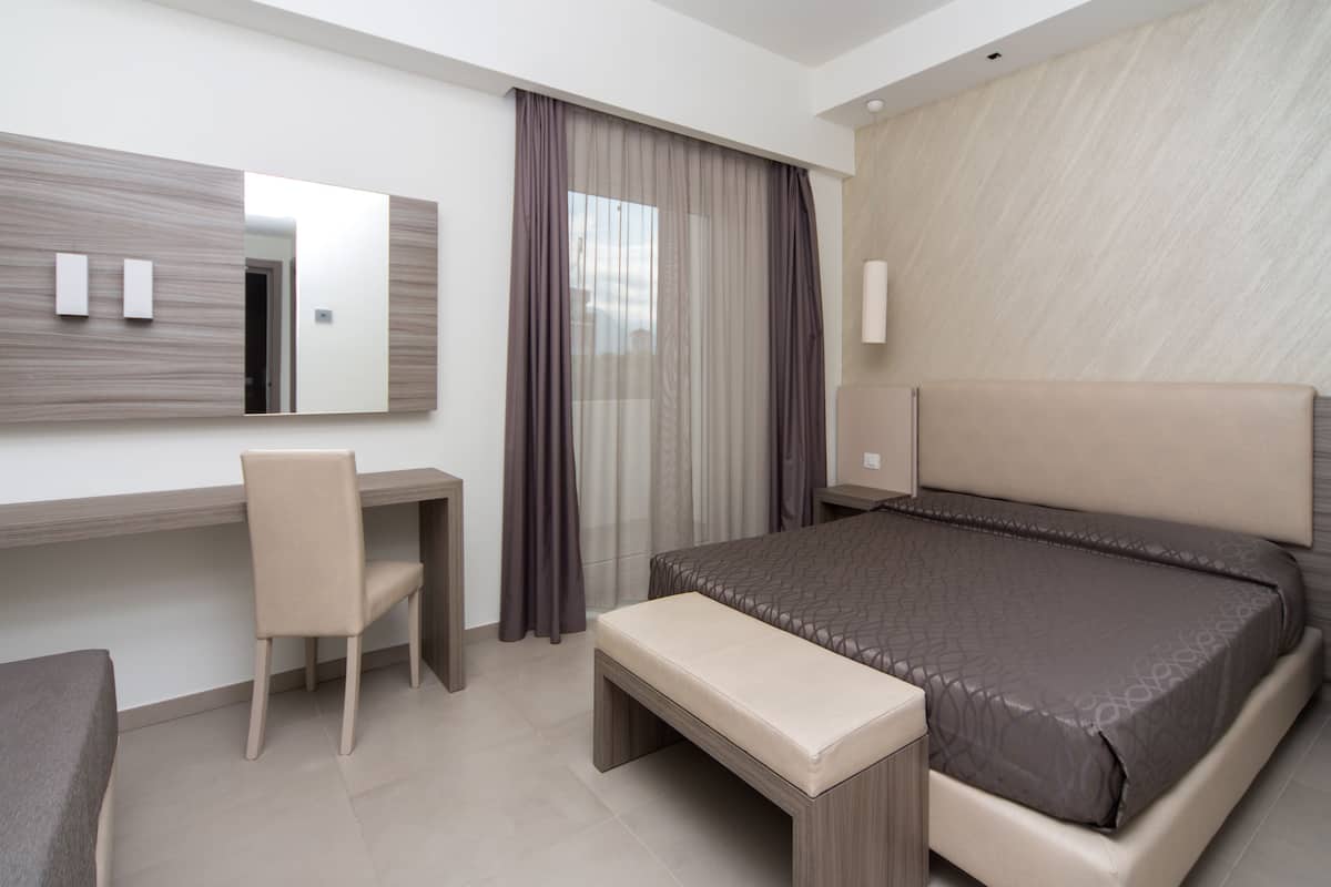Ein modernes Hotelzimmer mit einem großen Bett, einem Schreibtisch, einem Stuhl und einer Bank.