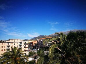 A residential area with multi-story buildings, a clear blue sky, and mountains in the background. - Hotel Village Club Santa Caterina (Scalea)