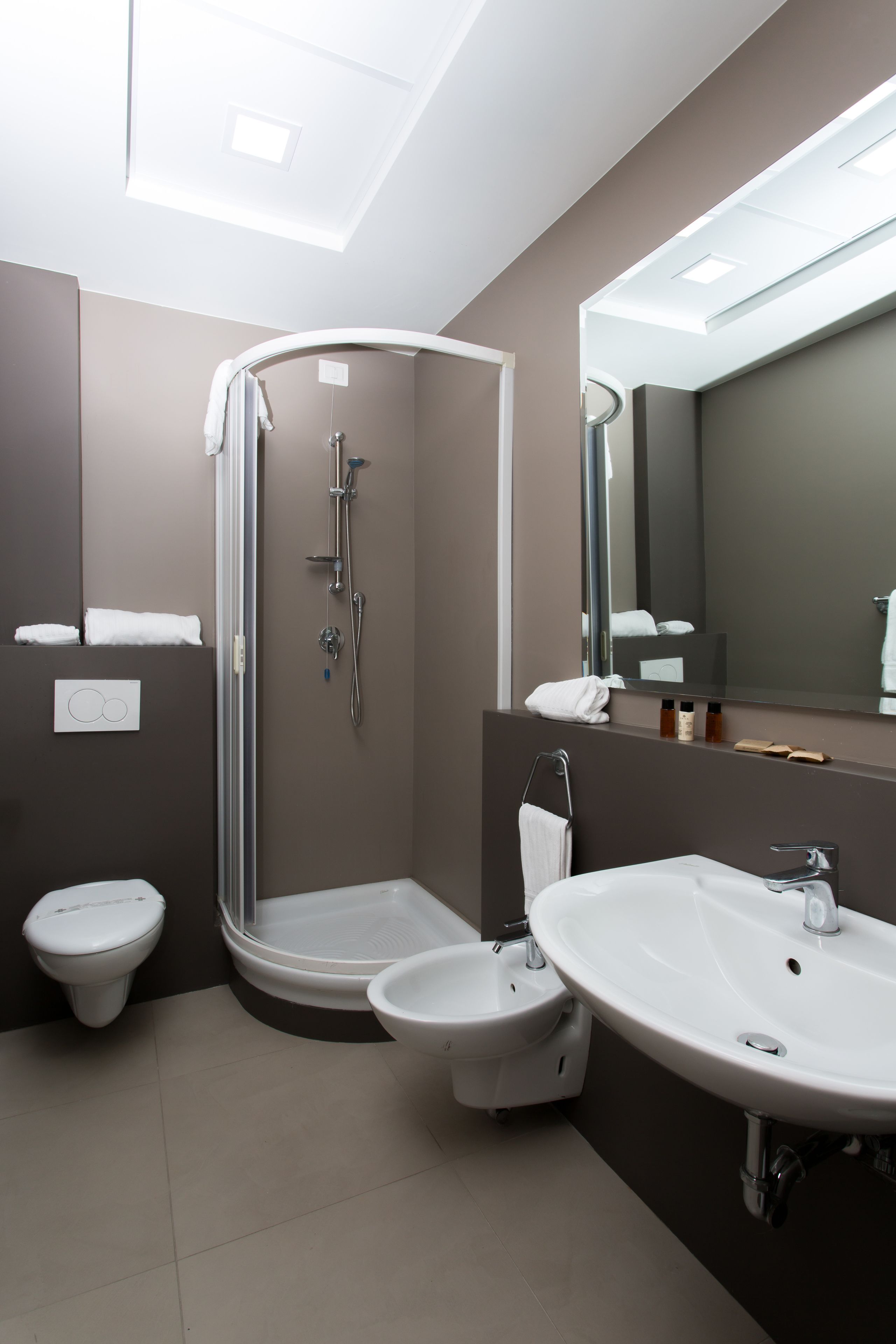 Un baño moderno con ducha, inodoro y dos lavabos.