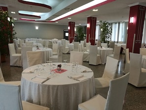 A banquet hall with round tables set for dining, white chairs, and a modern ceiling design. - Hotel Village Club Santa Caterina (Scalea)