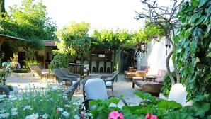A courtyard with wicker furniture, a white chair, and a variety of flowers.
