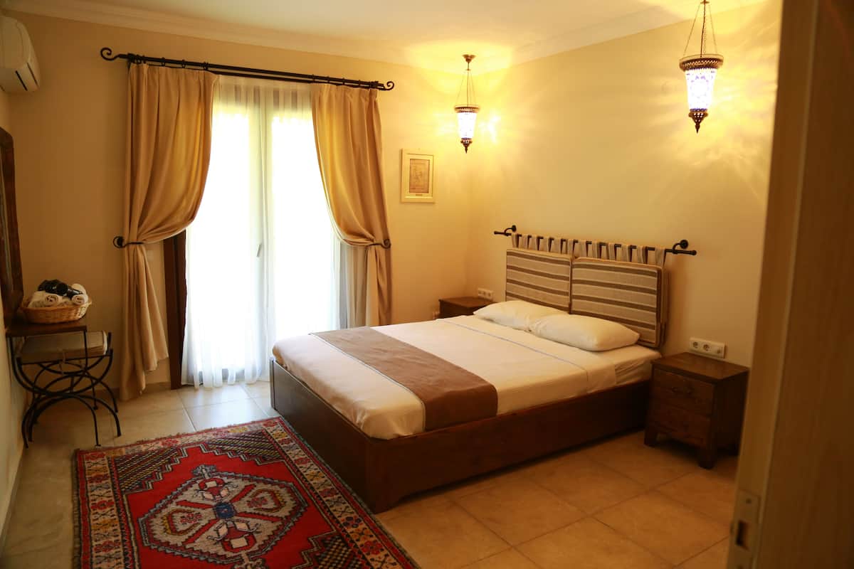 A bedroom with a bed, nightstands, a rug, and a window with curtains.
