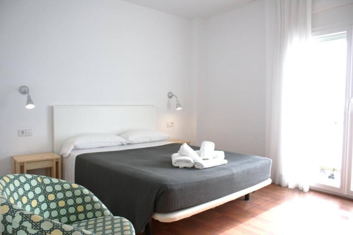 A bedroom with a bed, bedside tables, a chair, and a window with curtains.