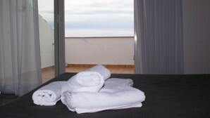 A bed with neatly folded white towels and a view of the sky through a glass door. - Hotel Vila de Premià (Premia de Mar)