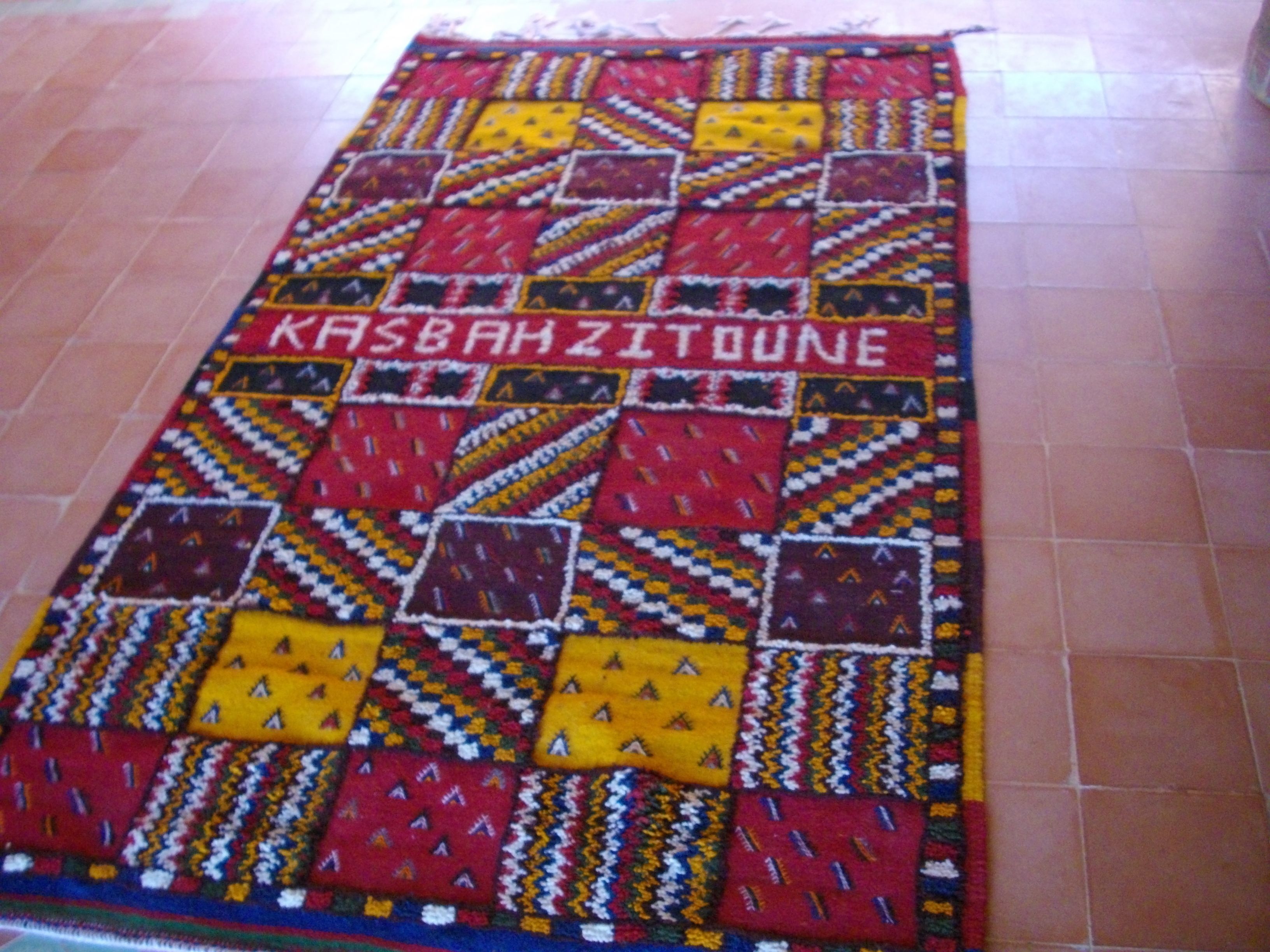 Ein farbenfroher, gemusterter Teppich mit dem Aufdruck 'KASBAH ZITOUNE'.