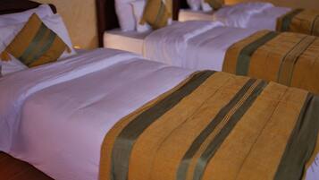 Two beds with white and striped bedding, wooden headboards, and a wall-mounted control panel.