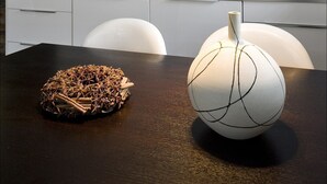 Une cuisine moderne avec une table en bois foncé, une lampe sphérique blanche et une boule décorative contenant des épices.