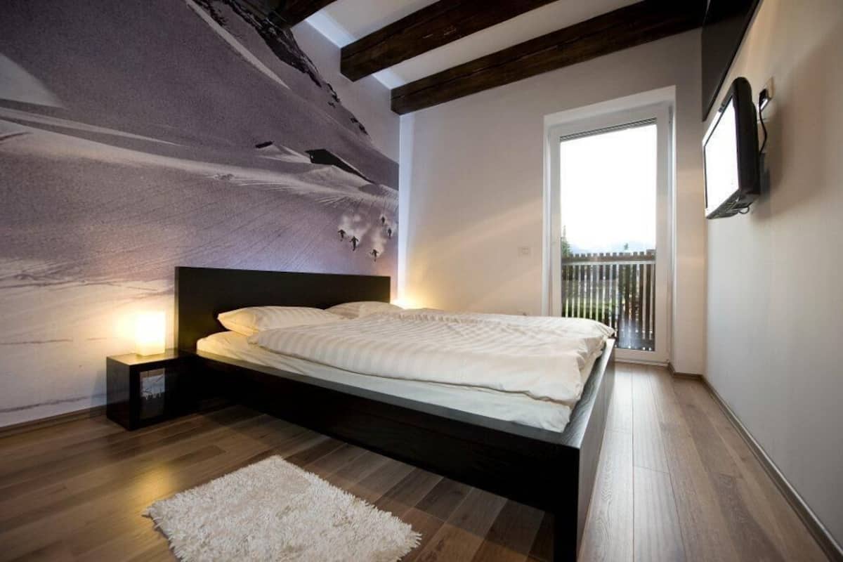 Une chambre à coucher moderne avec un grand lit, une table de chevet, un tapis blanc et une fresque murale.