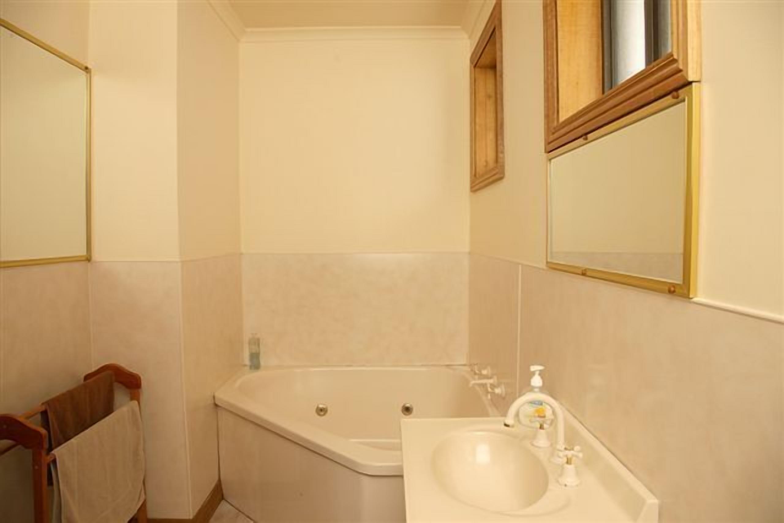 A bathroom with a bathtub, a sink, and a mirror.