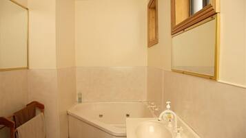 A bathroom with a bathtub, a sink, and a mirror.