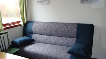 A modern living room with a grey sofa, a wooden table, and two framed artworks on the wall.