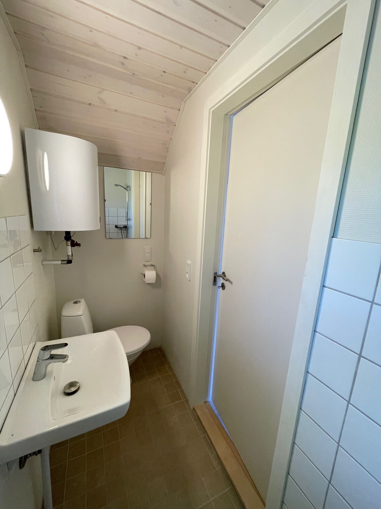 A small, clean bathroom with a white sink, toilet, and a mirror above the sink.