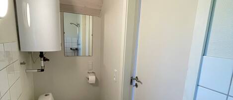 Une petite salle de bain propre, avec un lavabo blanc, des toilettes et un miroir au-dessus du lavabo.
