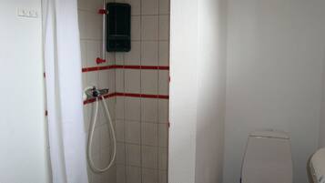 Een kleine badkamer met een douche, toilet en een rode zitting.