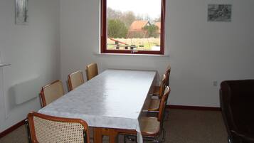 A conference room with a long table and six chairs, a window with a view of a playground, and a radiator on the wall.