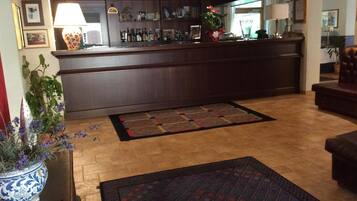 A hotel lobby with a bar area, a patterned rug, and a potted plant.
