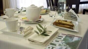 A neatly arranged breakfast table with a teapot, cups, a glass, and a plate of toast.