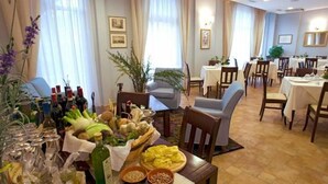Un comedor con mesas dispuestas para comidas, una variedad de alimentos y bebidas sobre ellas, y diferentes opciones de asiento como sillas y un sofá.