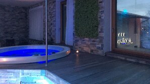 Un área de piscina interior moderna con una pared de piedra y un vidrio que da al exterior.